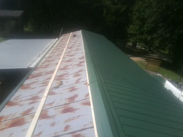 Old rusted panels beside newly installed green metal roofing — Wind Damage Roof Repair by Roofing Brothers in Rochelle
