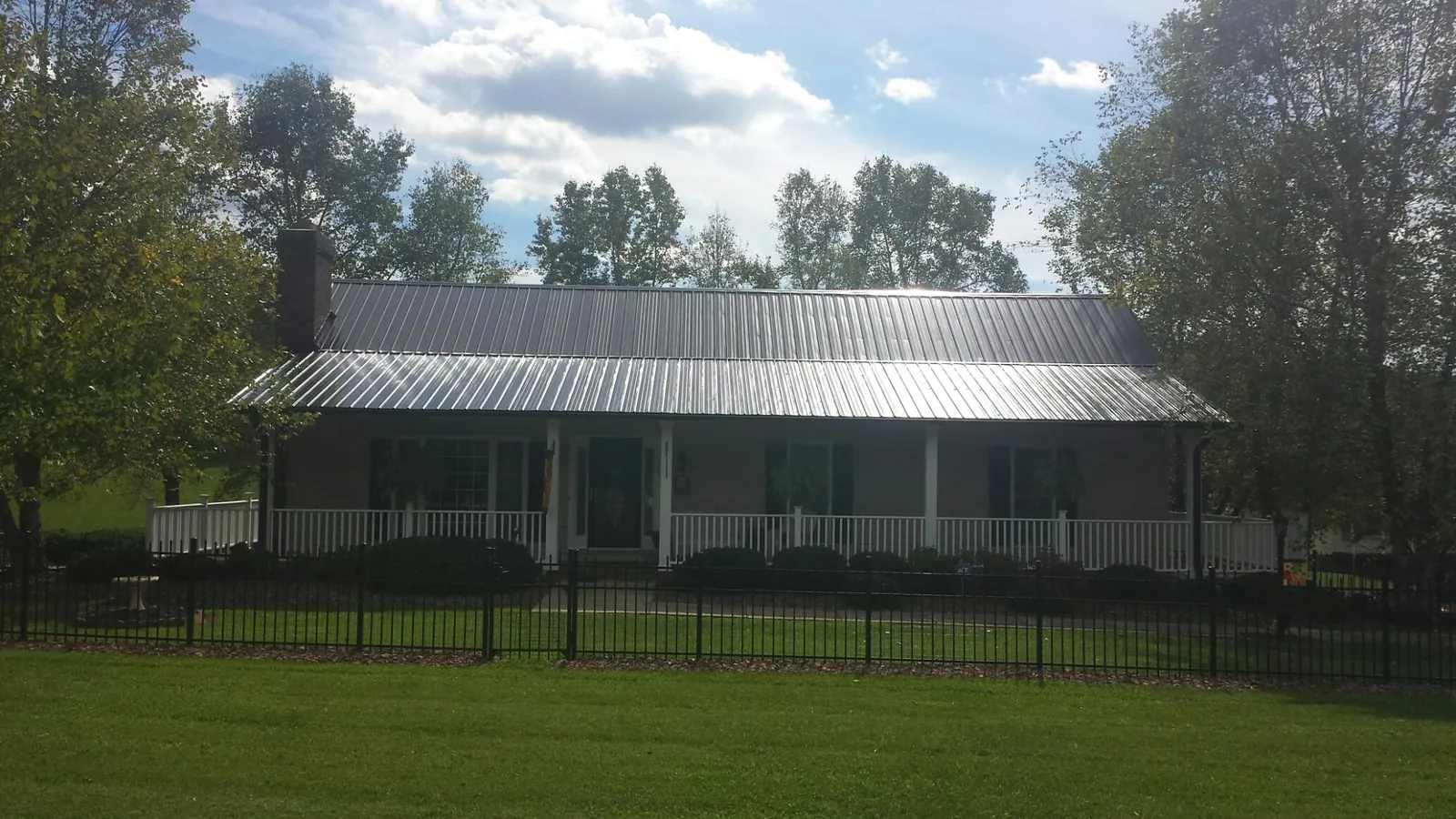 Gray metal roof on a brick ranch with a full width front porch — Gutter Guard Installation work by our crew in Rochelle